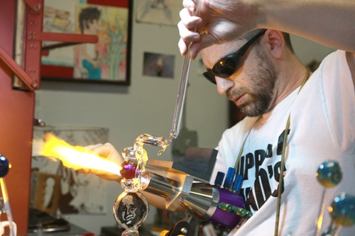 Gordon Bates / Arizona Summer Wildcat
Micah Blatt, owner of Fathead Custom Glass in Tucson, performs the challenging procedure by which most of todays popular glass smoking utensils are made. Micah has been in the business for well over 10 years and his shop is filled with work of his own as well as that of other local and national artists.
