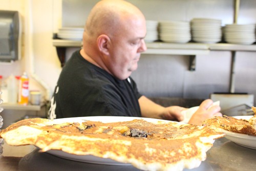 Lisa Beth Earle/ Arizona Daily Wildcat

Steve Hughes cooks behind a plate blueberry and banana pancakes at Bobos Restaurant on Tuesday, April 6. The restaurant is known for serving pancakes that flow over the plates.