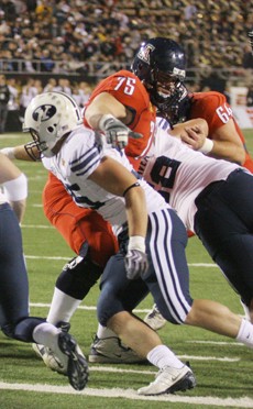 Former UA offensive guard Joe Longacre splits a pair of BYU defenders in a 31-21 Las Vegas Bowl win in December at Sam Boyd Stadium. Longacre and four other Wildcats took part in NFL mini-camps during the weekend.