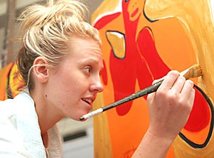 Fine art studies senior Britt Smith puts strokes to her canvas to create contrast for her figure during her painting 380 course. I love the freedom to express yourself each day, said Smith.