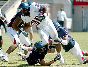 UA running back Chris Jennings carries the football while being grabbed by linebacker Jeremy Samoy (57) and safety Nate Ness during Saturdays Spring Game at Arizona Stadium. Jennings rushed for 39 yards on eight carries in the game, which marked the end of spring practice for the Wildcats.