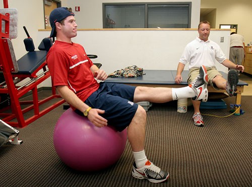 UA tennis player Jay Goldman works out with team trainer Adam Garmon in the training room of McKale Center on Tuesday to strengthen his back after injuring it March 22 against ASU. Goldman, a freshman, hopes to be back in action this weekend against UCLA and USC or the following weekend against ASU.