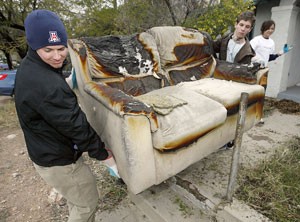 Physiology senior Tom Fernandes and undeclared freshman Pete Zolezzi take a burned couch from a porch at a project house near East Broadway Boulevard and North Mountain Avenue. The UA Mortar Board organized 14 teams into a mass effort to clean up the streets immediately north and south of campus.