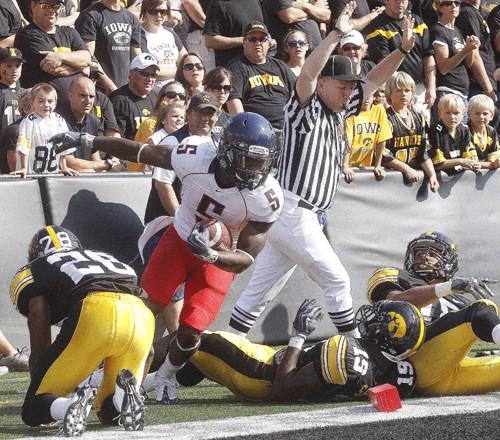 Running back Nic Grigsby jumps to his feet after being knocked out of bounds by three Iowa defenders.