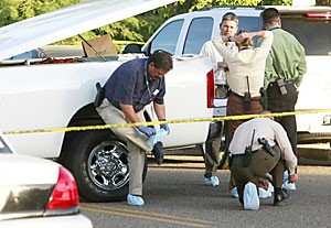 Tucson Police Department officers don shoe protectors before entering a house at the southeast corner of East Third Street and North Norton Avenue. A victim described as a young man in his early 20s was found dead inside the house yesterday.