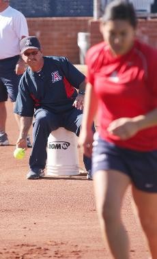 UA softball head coach Mike Candrea tosses a ground ball during practice on Tuesday at Hillenbrand Stadium. Candrea returns to Arizona to lead the Wildcats this season after taking last year off to take charge of the U.S. Olympic team.