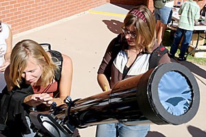 Amber Ashby, a junior majoring in English, and Sara Drake, a family and consumer science education junior, look through a telescope in front of Flandrau Science Center yesterday afternoon. Telescopes were set up for public viewing as the planet Mercury passed in front of the sun.