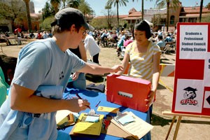 Vince Martinson, an insect science doctoral student, drops his ticket into the raffle ticket box held by Jodi Burshia, the GPSC event director, during the GPSC election held yesterday afternoon on the UA Mall. 