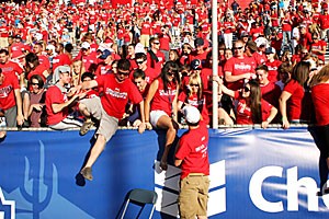 Zona Zoo members jump the fence before rushing the Arizona Stadium field Saturday after the UA football teams 34-27 win over UCLA. It marked the third straight Homecoming after which Arizona fans rushed the field.