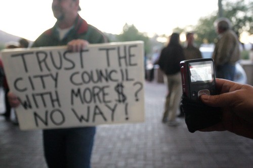Mike Christy/ Arizona Daily Wildcat

Oro Valley resident Mike Shaw takes a picture with his cell phone of John Hendersons protest sign prior to the Tucson city council meeting Tuesday, Jan. 5, at the Tucson Convention Center.
