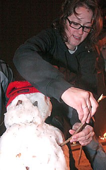 Pre-business freshman Liz Bauma puts the finishing touches on a snowman Sunday night on the UA Mall. Students from all over campus came outside when they heard snow was falling. 