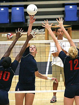 Outside hitter Brooke Buringrud hits the ball over leaping middle blockers Dominique Lamb (10) and Jacy Norton (12) while head coach Dave Rubio observes in McKale Center yesterday. The Wildcats start their season tomorrow at home, which could have many disadvantages, Rubio said.