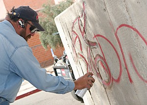 Andrew Davis from facilities management cleans the graffiti that filled the UA campus yesterday