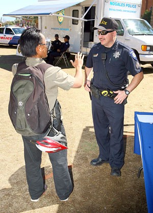 Percival Gou, a geology freshman, examines a pair of goggles designed to simulate the effects of alcohol while speaking to Sgt. Juan Alvarez of the University of Arizona Police Department during a spring break safety event held on the UA Mall yesterday afternoon.