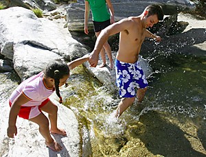 Alex Hoeckel, of Hagerstown, Md, tries to coax four-year-old Makyah Baker into the cold waters of Sabino Creek. With the recent rain and mountain snow, Sabino Creek is flowing. (Chris Coduto/Arizona Daily Wildcat)