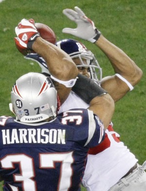 New York Giants receiver David Tyree, right, leaps to catch a 32-yard pass as New England Patriots safety Rodney Harrison (37) tries to defend during the fourth quarter of the Super Bowl Sunday in Glendale. Somehow, with time running out and the ball pinned to his helmet, Tyree held on tight with both hands Sunday.