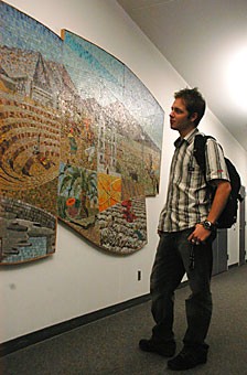 Pre-business sophomore Stuart Holst studies a mural in McClelland Hall yesterday evening. The university would like to see local artists work displayed in all university buildings.