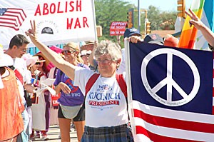 Alice Hamer throws up the peace sign while she walks in the antiwar march Saturday morning. Hundreds of protesters gathered at the UA Main Gate on University Boulevard and marched east on Speedway Boulevard to the De Anza Park on North Stone Avenue. 