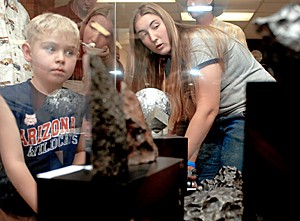 Laura Killgore, right, who lives and is home schooled in Tucson, explains the meteorites on display to a young boy. She and her father, Marvin Killgore, started Southwest Meteorite Center, the first organization that will help people who find meteorites sell their alien rocks.