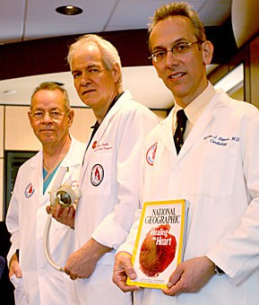 Dr. Jack G. Copeland, professor of surgery and director of Cardiac Transplant and Artificial Heart Programs, left, Richard Smith, MSEE, CCE Chief Technical Officer, and Dr. Marvin Slepian, clinical professor of medicine and director of interventional cardiology, stand with a Total Artificial Heart and the latest issue of National Geographic, which highlights the device. The artificial heart is a temporary implant that allows patients to survive until a real heart becomes available.