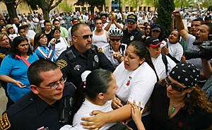 Tucson police walk 16-year-old Marisol Garcia (lower center) away from Armory Park yesterday afternoon after police suspected her of throwing a bottle at protestors who set the Mexican flag ablaze. (photo by chris coduto/arizona daily wildcat)