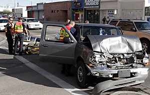 Tucson Police and firefighters assist an unidentified woman after she crashed into several cars and a lightpost on East Sixth Street yesterday. She was taken by ambulance to University Medical Center.