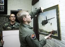 Left, Cadet Benjamin Rogers, a senior majoring in French, and Dan Larkin, a molecular and cellular biology senior, hang two pieces of aviation art donated to the ROTC Air Force program by Hugh Jordan, a police aid for UAPD, only moments earlier in a ceremony in the South Hall ROTC building on Monday afternoon.