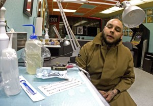 Isaiah Camacho, owner of the tattoo parlor Staring Without Caring, sits beside strewn out sanitizing equipment Monday night. Due to upcoming Arizona laws body art establishments will need a license from the Pima County Health Department and subject to its regulations.