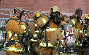 Firefighters don gas masks outside the Harshbarger building yesterday in response to an argon gas leak resulting from a broken tank.