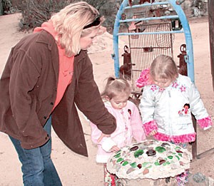 Sisters Nadali Greenwood, 2, and Kadee Greenwood, 3, stop with their mother Kristi Greenwood during the Valley of the Moon tour to take a look at the mystical creations that decorate much of the park. During their tour of the Tucson fantasy park, visitors can expect to see fairies, live music and costumed oddities.