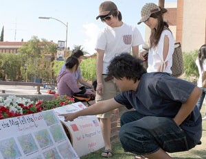 Quingyan Zhang, a pre-business freshman, shows Frank Zhou, a business freshman, left, and Chu Chu, a Pima Community College media arts freshman, right, a poster depicting China during different time periods. Chinese students put on a display depicting China in a good light, without all of the politics surrounding the Summer Olympics.