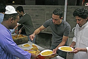 Electrical engineering junior Ahmad Adas and Abdullah Alshmmari, an environmental science graduate student, serve food to Abdul Kadir, 26, at the Islamic Center of Tucson last night. The Islamic holiday Ramadan began this weekend, and attendees broke their traditional daily fasts with a large community dinner after sunset.  
