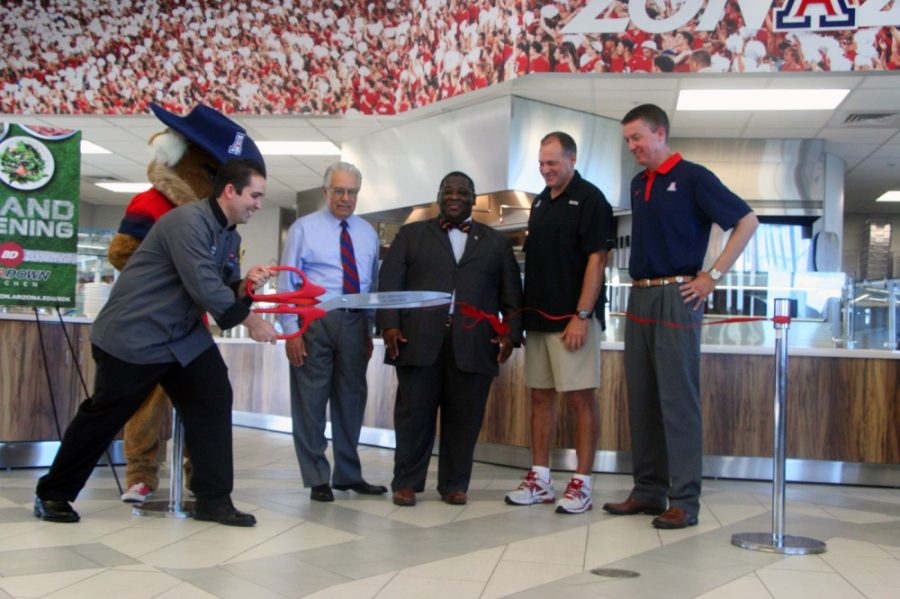 Michaela Kane / The Daily Wildcat

Zachary Baker cuts the ceremonial ribbon at the grand opening of Bear Down Kitchen on Tuesday while (from left)Wilbur the Wildcat, Frank Farias, Jason Rex Tolliver, Rich Rodriquez, and Greg Byrne look on. 