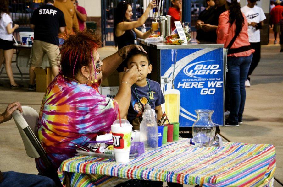 Rebecca Noble/ Arizona Daily Wildcat

The Mistress of Color, Mary Wilkinson, paints Isaac Cecenas face at the Vamos a Tucson Mexican Baseball Fiesta on Thursday night.
