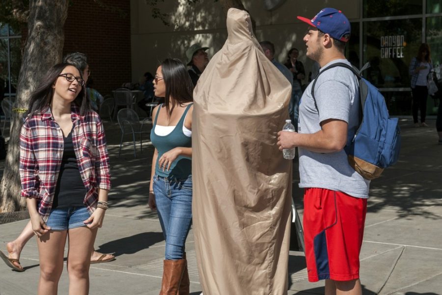 Carlos Herrera / The Daily Wildcat

Brittany Santini, Celine Tang, and Dhillon Sandhu hand out free condoms as Nicholas Plumlee models a 6 foot condom suit during Campus Health Services annual Sexual Health Resource Fair on Wednesday. 