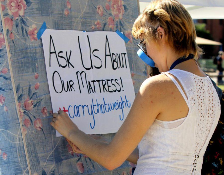 Simone La Londe, a sophomore studying public health and Spanish, tapes a sign to a mattress during Feminists Organized to Resist, Create and Empowers sexual assault booth on the UA Mall on Wednesday. FORCE included a mattress at its table to show solidarity with Emma Sulkowicz, a student at Columbia University who is carrying around the mattress upon which she was sexually assaulted until her rapist is expelled from the university or she graduates.