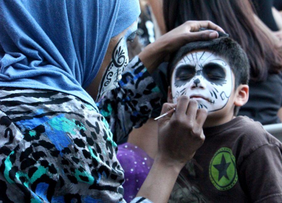Michaela Kane /  The Daily Wildcat

Tamina Muhammad, a painter with Face Flip facepainting, paints a childs face before the start of the Dia de los Muertos parade on Sunday, Nov. 3, in downtown Tucson. 