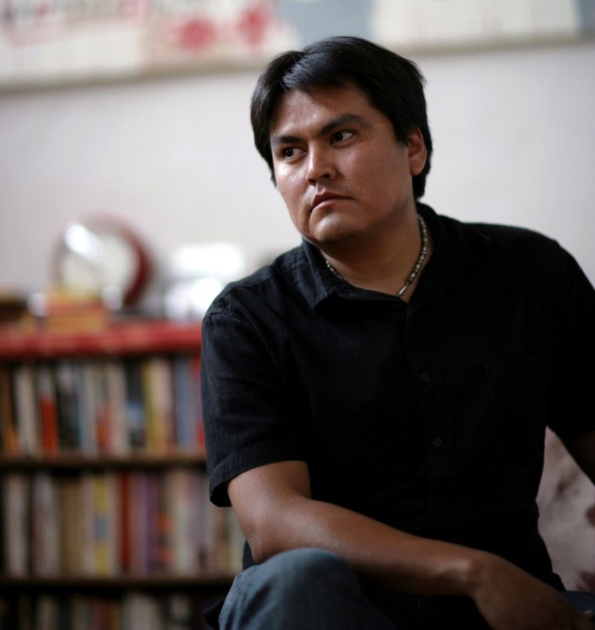 Courtesy of UA Poetry Center Sherwin Bitsui, a Navajo poet, sits in front of a bookcase. Bitsui will be reading his work at the Poetry Center on Thursday as part of the Poetics and Politics of Water series.
