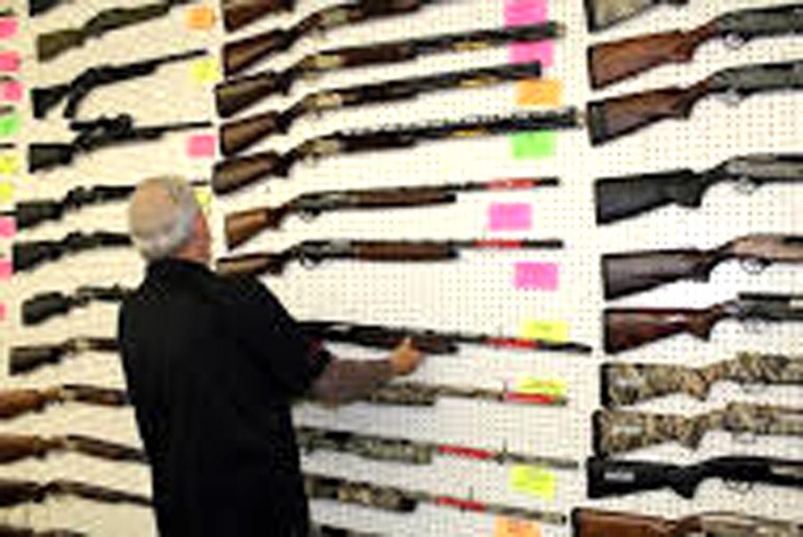 Brittney Smith / Arizona Sonora News ServiceClay Wood, an employee at Second Amendment Sports, hangs a rifle on the wall. The outdoor sports store is one of many places to purchase a weapon in Tucson.
