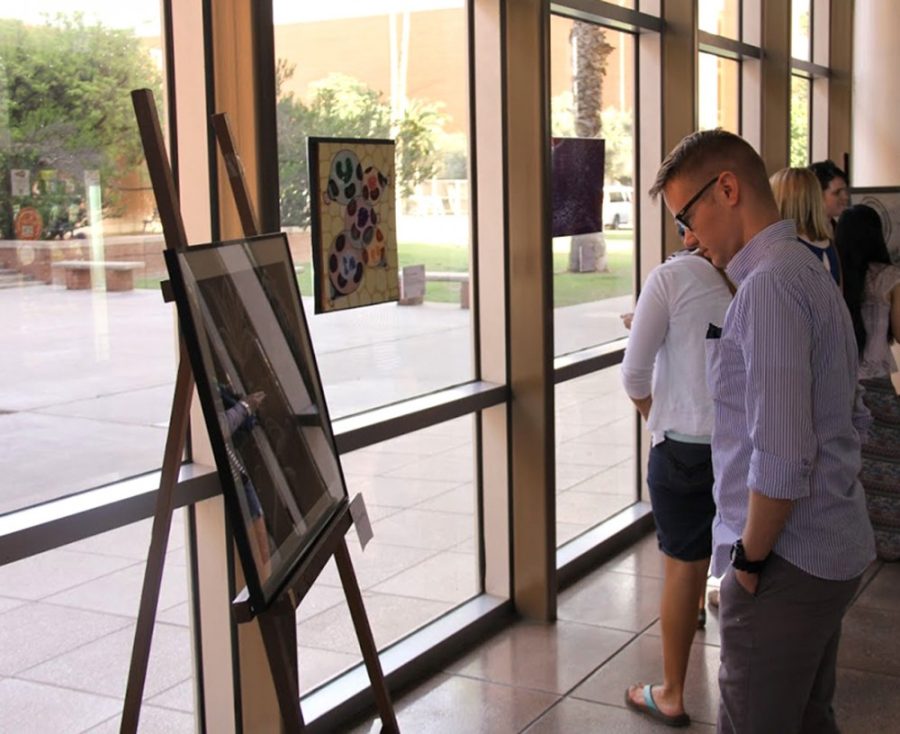 Adrian Ostertag, a senior studying neuroscience and cognitive science, contemplates a piece of artwork at Nu Rho Psis and the Neuroscience & Cognitive Science Ambassadors art showcase fundraiser on Monday in the main lobby of the Gould-Simpson building. Students and faculty submitted science-themed art for public purchase.