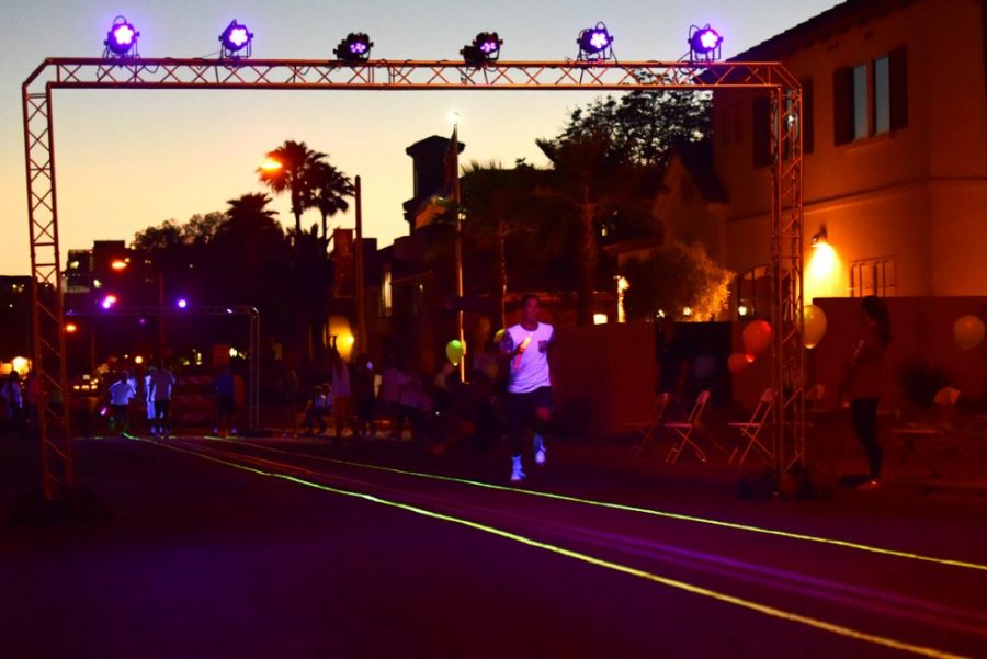 A participant in Gamma Phi Betas Go for Glow philanthropy event sprints toward the finish line to pass off the glow baton during a relay race on First Street on Friday night. The purpose of the event is to spread awareness and raise money for colon cancer research.