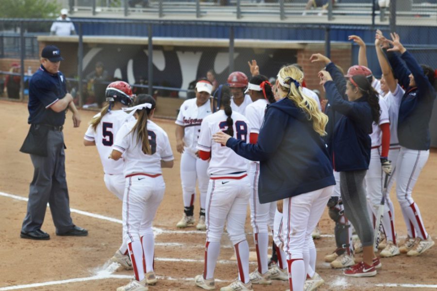 Arizona softball utility player Hallie Wilson (5) is greeted by her teammates at home plate after scoring a run during Arizonas 22-5 win against Stanford at Hillenbrand Stadium on April 26.