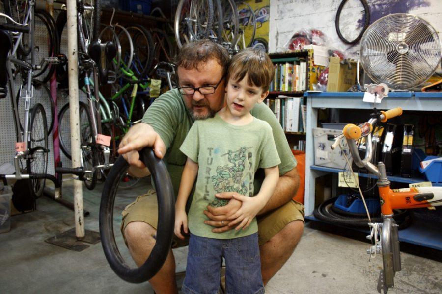 Baraha Elkhalil /  Arizona Summer WildcatScott Weiler points son Sam Weilers attention to a model bike while changing a flat tire at BICAS on Saturday, June 22.