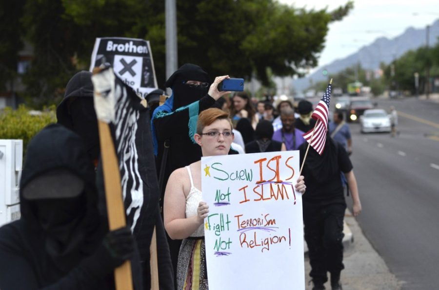 Sarah Murdoch, holding a sign and American flag, marches just ahead of Sumayyah Dawud, the Stand Up Against Hate rallys organizer, and alongside other protesters in the Anti-Colonial Anarchist Bloc on North Euclid Avenue just north of University Boulevard on Saturday, July 18, 2015. Murdoch, like many others, heard about the Stand Up Against Hate rally in advance through a Facebook event invitation.