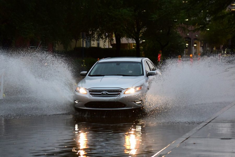 Rebecca Noble / Arizona Summer WildcatA car drives through several inches of water accumulated on Tyndall Avenue outside of Coronado and Arizona-Sonora Residence Halls on Tuesday, July 28. The lack of proper sewage systems throughout campus streets frequently causes flooding at intersections.