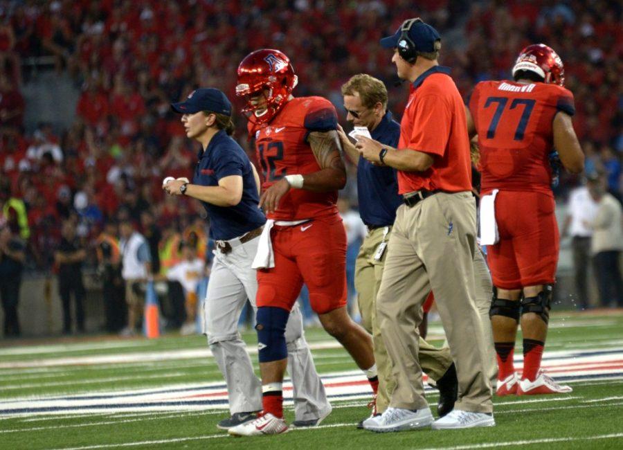 Officials escort Arizona quarterback Anu Solomon (12) off the field after he suffered a concussion while playing against UCLA at Arizona Stadium on Saturday, Sept. 26. Solomons concussions is just one of many injuries Arizona is dealing with. 