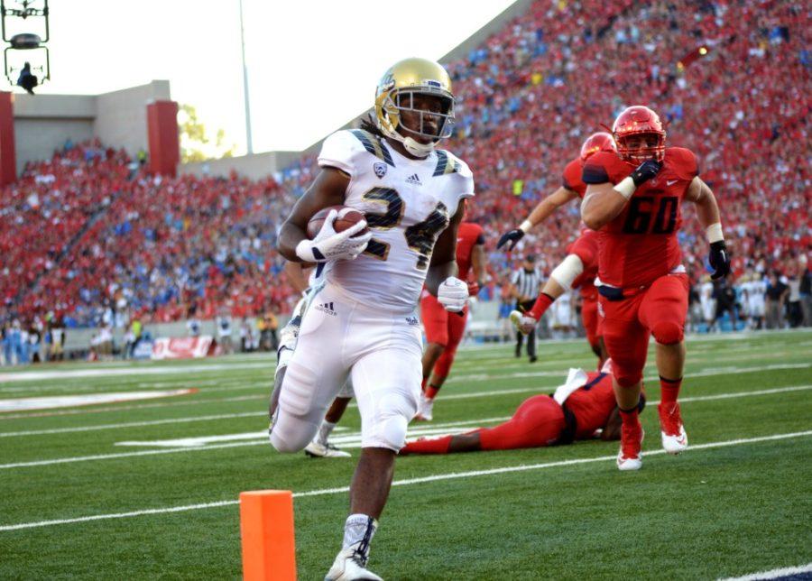 UCLA running back Paul Perkins (24) runs into the endzone for a touchdown at Arizona Stadium while Arizona defensive lineman Luca Bruno (60) gives chase on Saturday, Sept. 26. Perkins ran three touchdowns in the UCLA victory. 