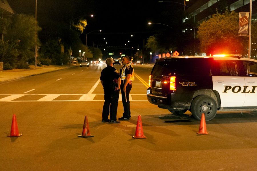 Two Tucson Police Department officers talk while manning a traffic cone roadblock on Euclid Avenue just south of Speedway Boulevard. The officers responded to a pedestrian who was struck by a vehicle. The victim sustained non-life-threatening injuries and is expected to recover.