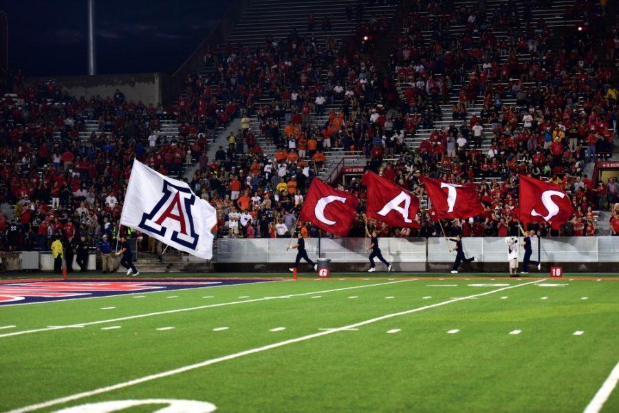 UA cheerleaders run Arizona flags around the field before the Wildcats first football game of the season against UTSA at Arizona Stadium on Thursday, Sept. 3.