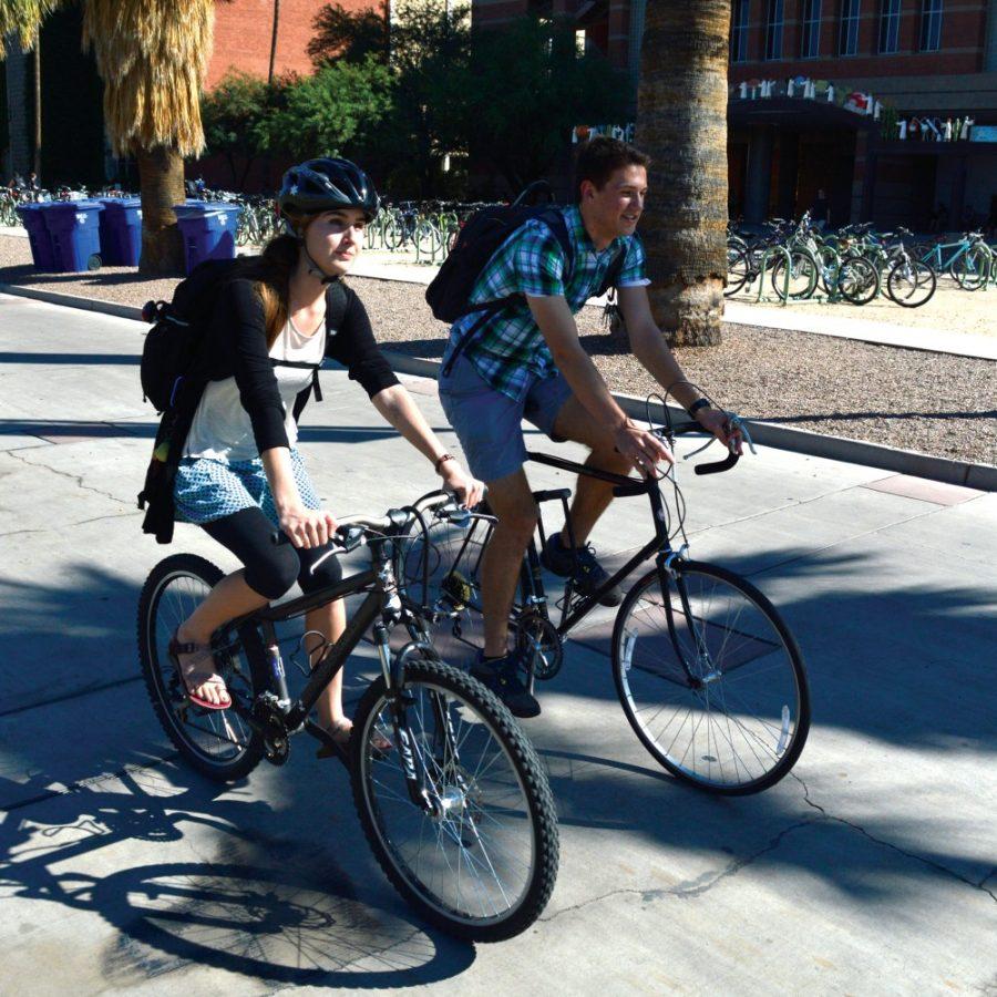 Sarah MacKenzie, Speech, Languages & Hearing Sciences Senior, and Kevin Morris, Electrical Engineering Senior, ride bikes together after a day of classes. Mackenzie wears her helmet because she doesnt trust the traffic on campus, Morris owns a helmet and says he is too lazy to wear it when he rides. 